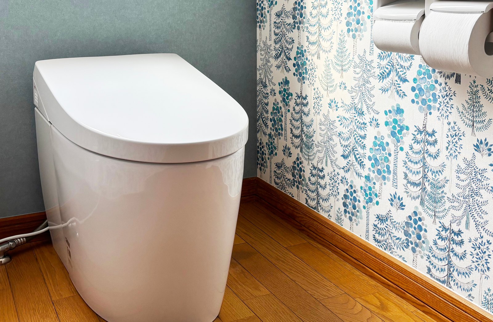 施工後のトイレ。凹凸の少ない便器と、アクセント壁紙側の紙巻器